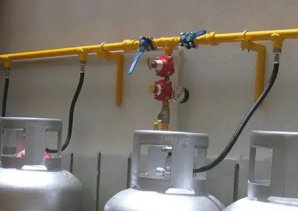 Central de GLP de alta pressão com múltiplos cilindros cinzas e tubulação amarela instalada.
