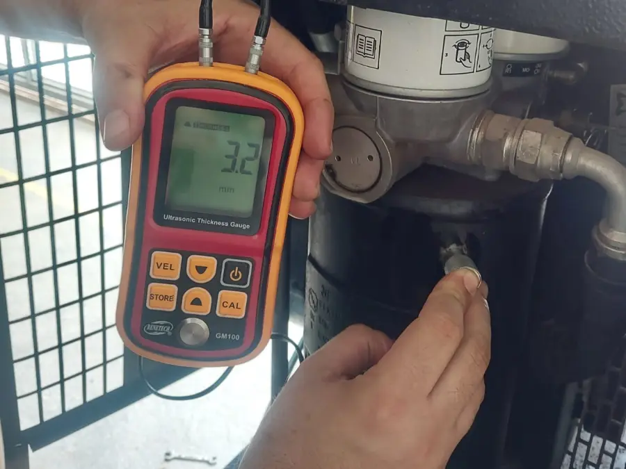 Técnico da Eletro Contato medindo a espessura do vaso de pressão de um compressor de ar com medidor por ultrassom
